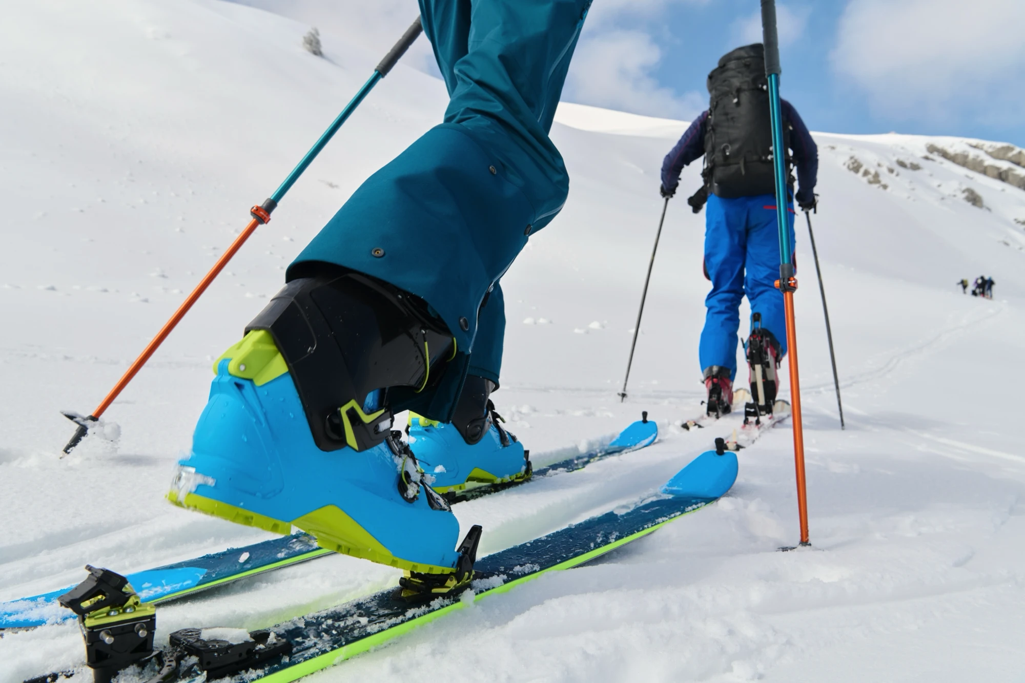 Skiers climbing snowy mountain with skis and poles in winter.
